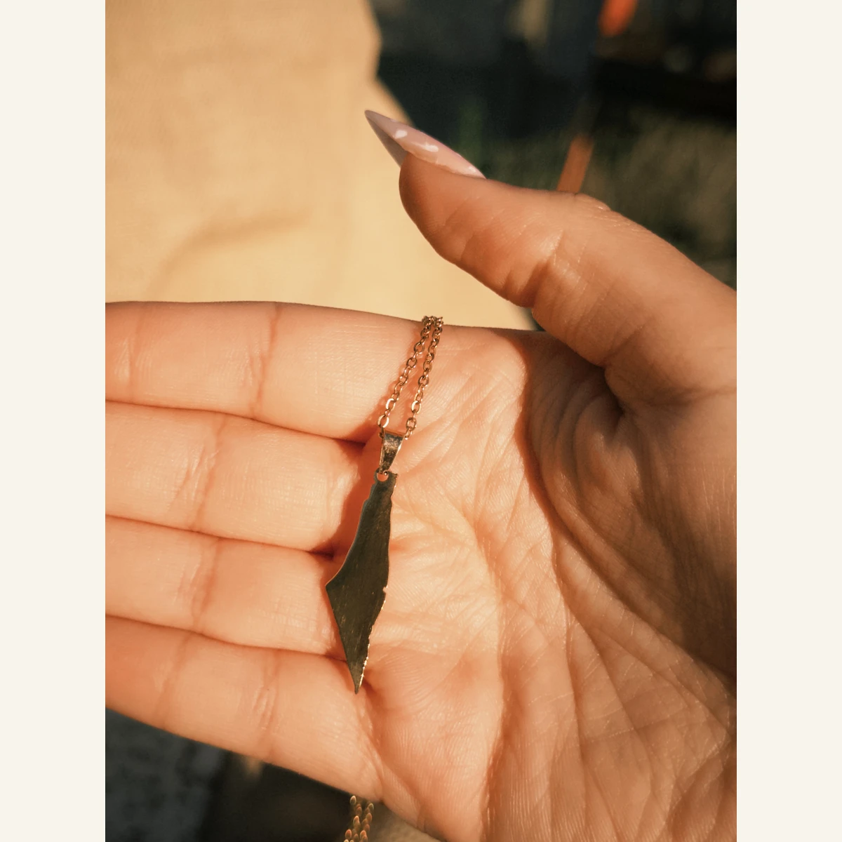 Golden Palestine Map Necklace held in hand to show its size