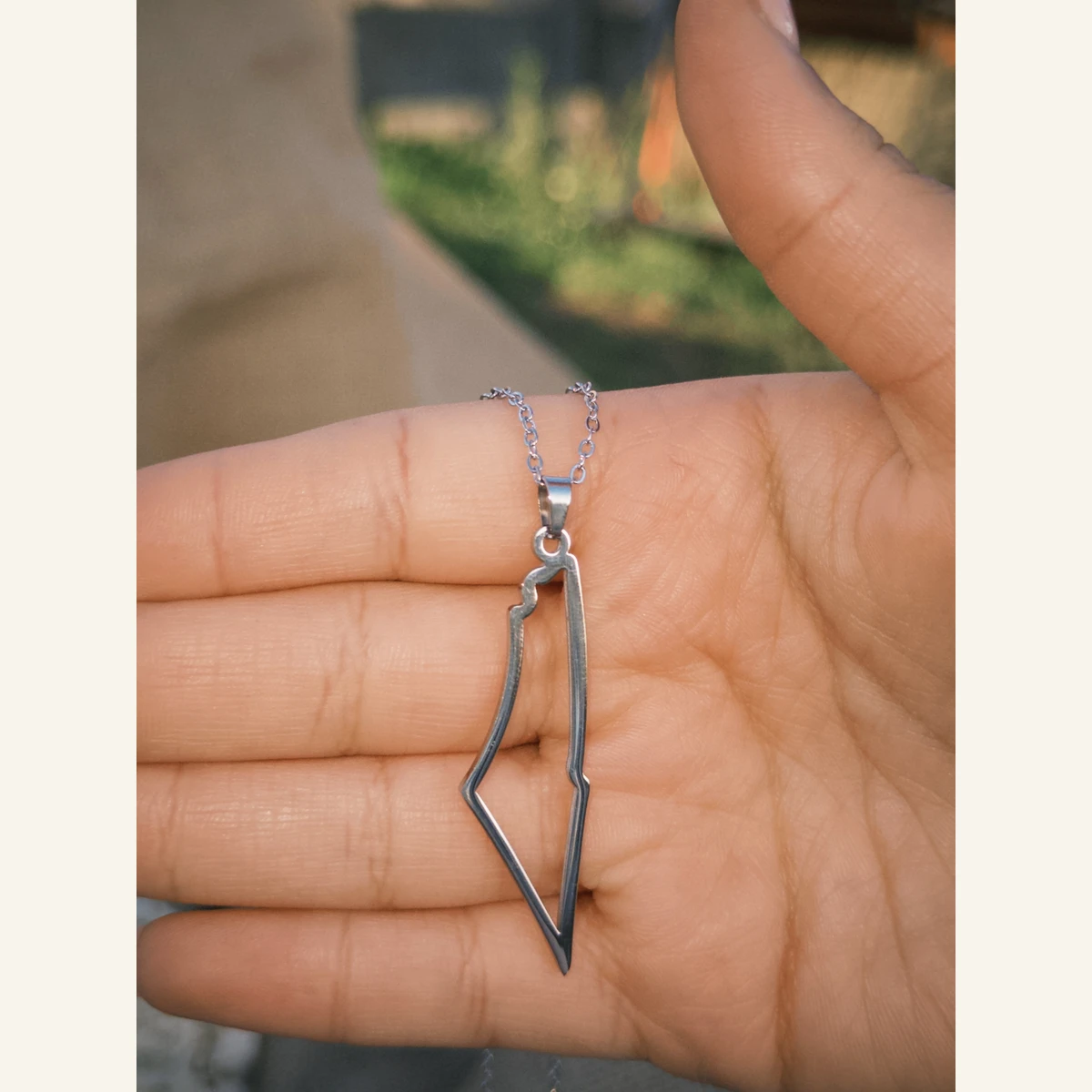 Palestine Outline Necklace held in hand to show its size