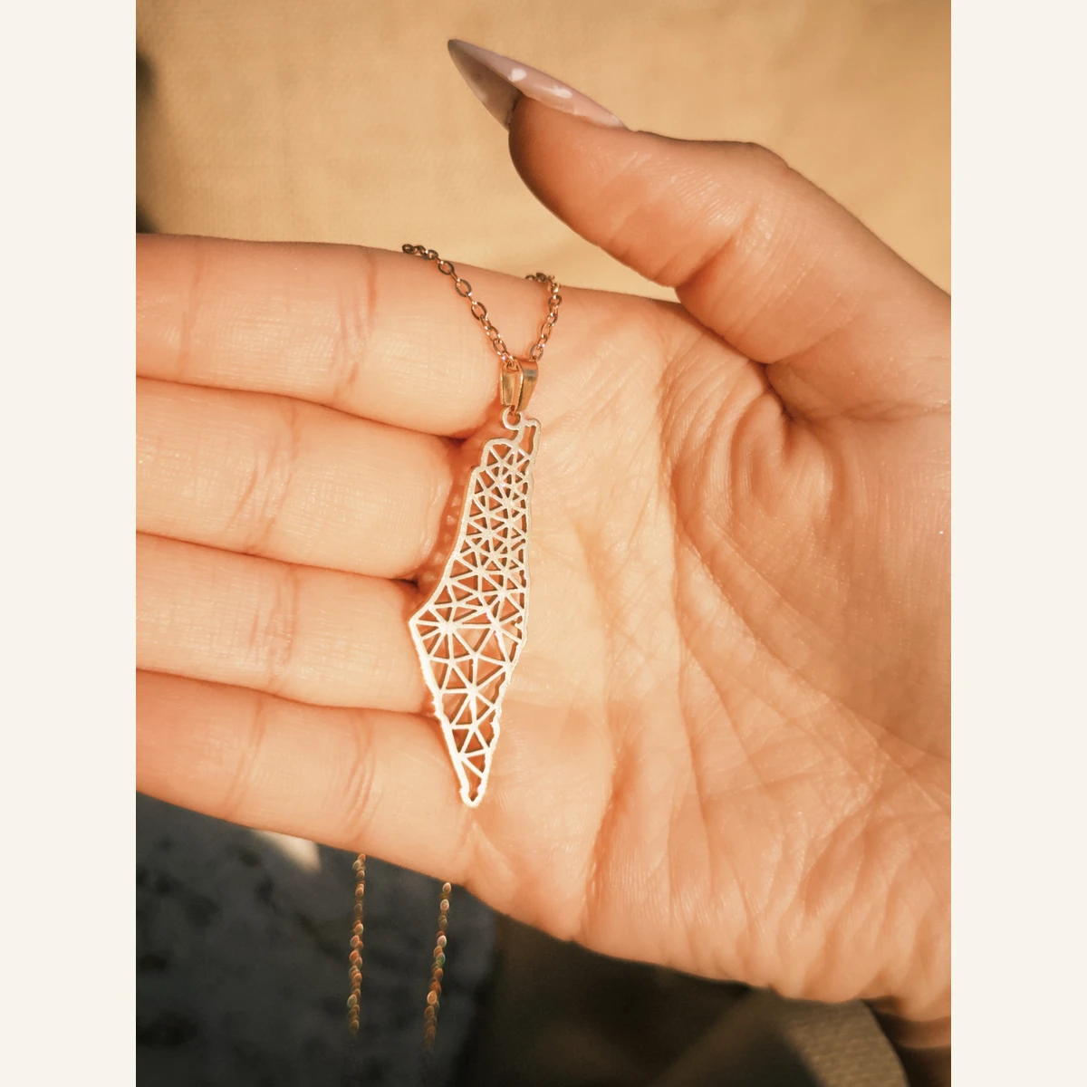 Golden Geometric Palestine Necklace held in hand to show its size