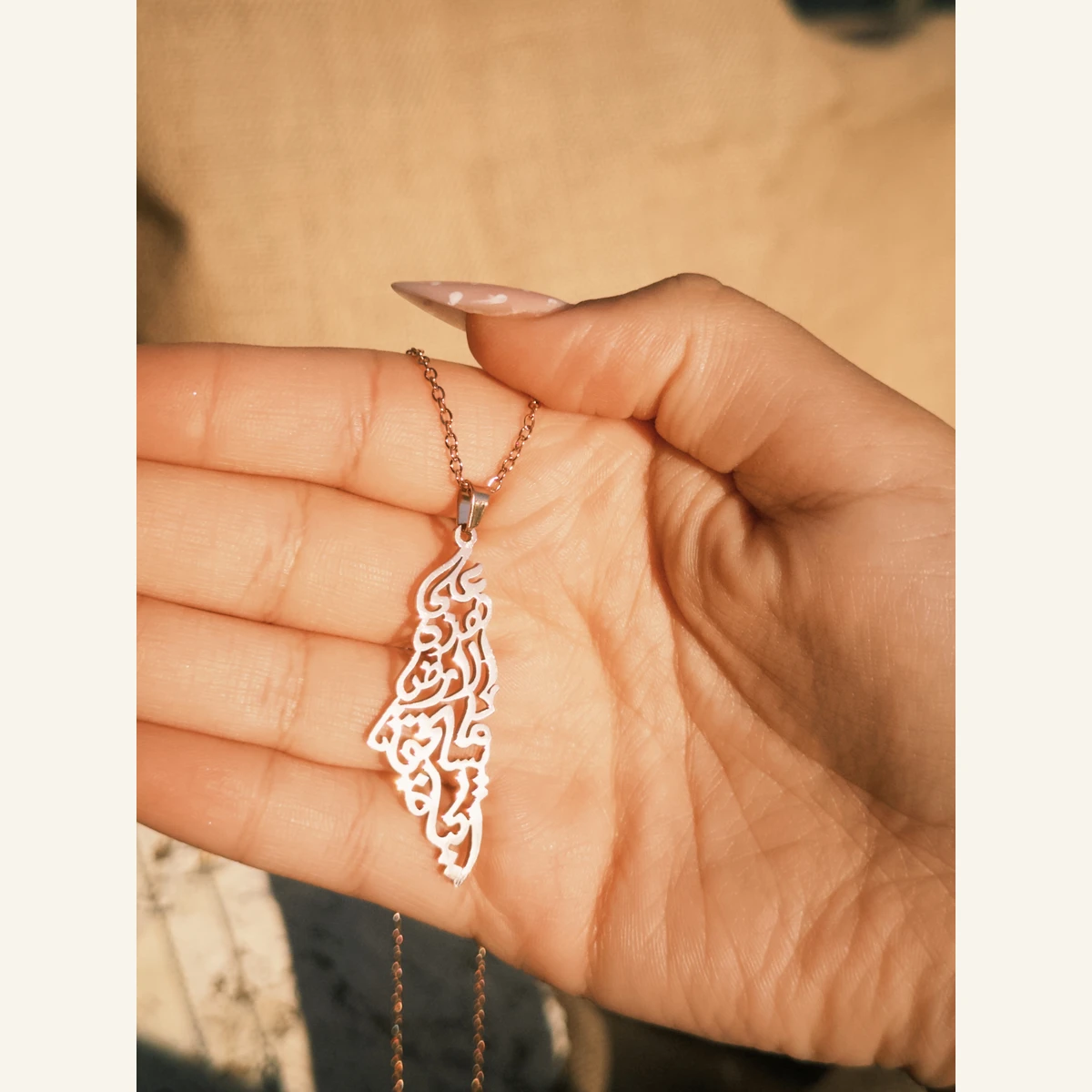 Palestine Calligraphy Necklace held in hand to show its size
