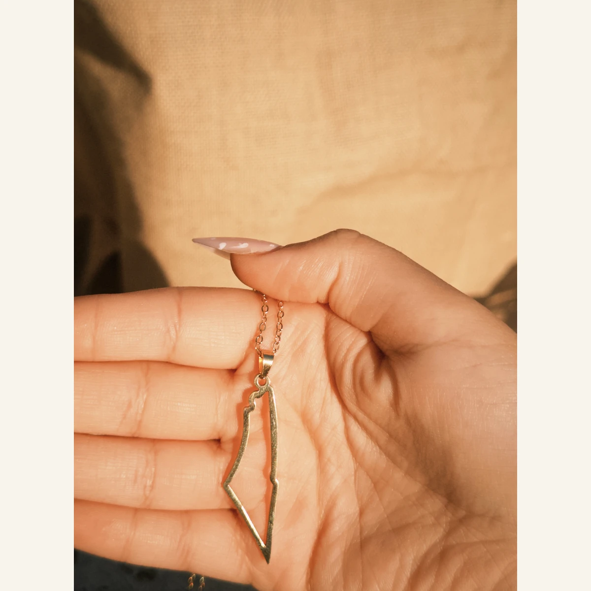 Golden Palestine Outline Necklace held in hand to show its size
