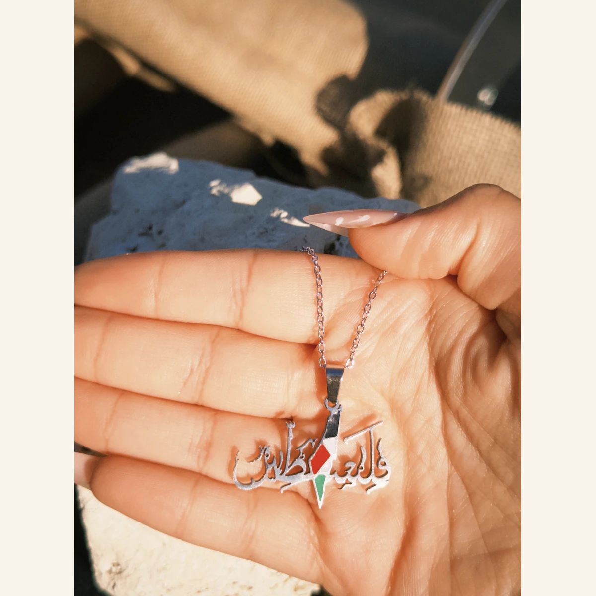 Filastin Flag Necklace held in hand to show its size