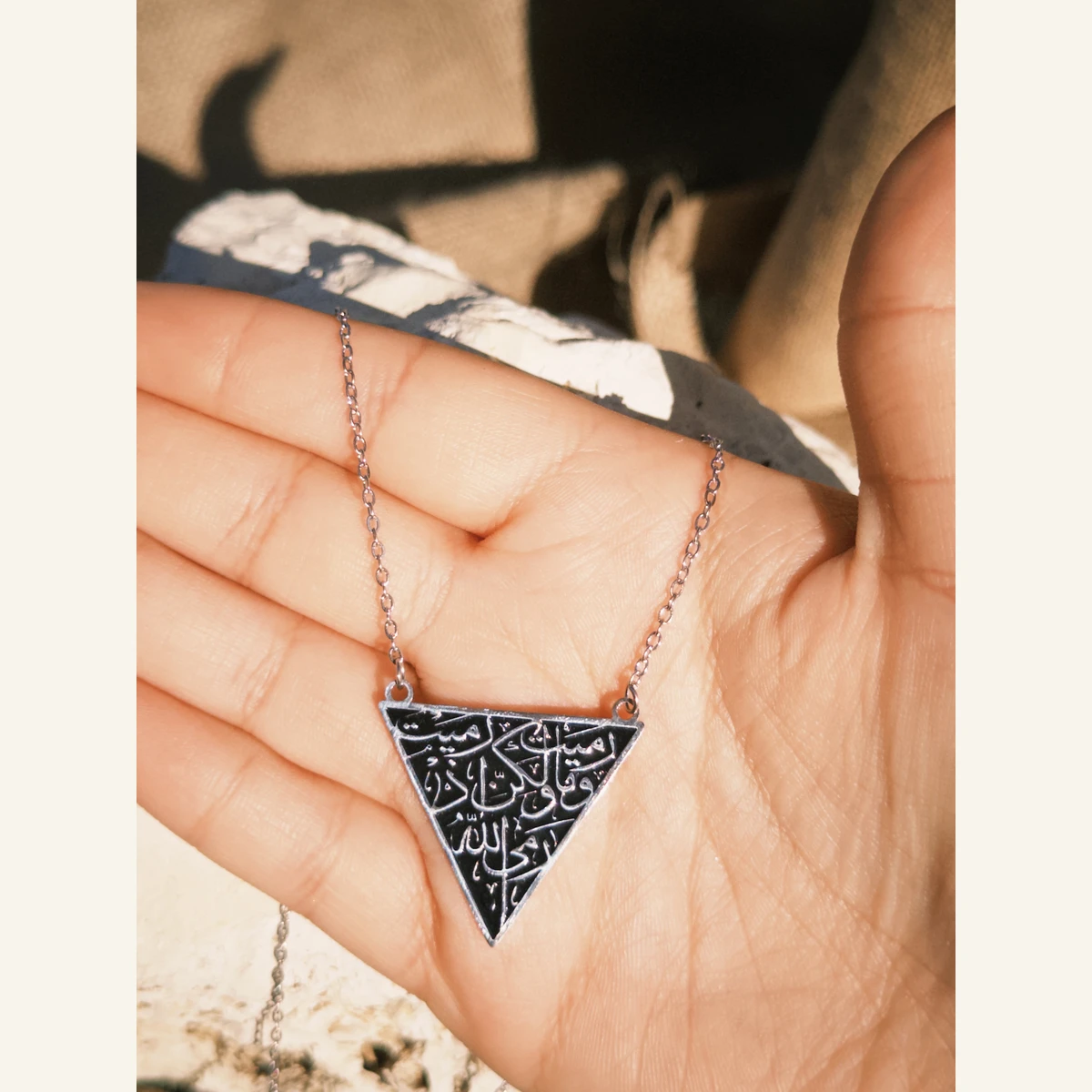 Black Triangle Calligraphy Necklace held in hand to show its size