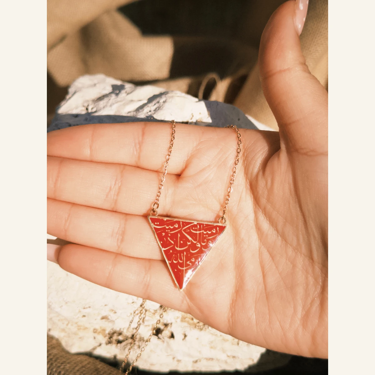 Red Triangle Calligraphy Necklace held in hand to show its size